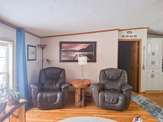 sitting room with ornamental molding, light hardwood / wood-style flooring, and a textured ceiling