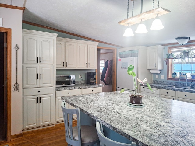 kitchen featuring white cabinetry, sink, hanging light fixtures, ornamental molding, and white appliances