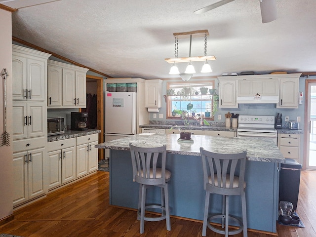 kitchen with a kitchen island, white cabinetry, a kitchen breakfast bar, dark wood-type flooring, and white appliances