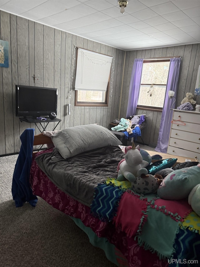 bedroom featuring wood walls and carpet