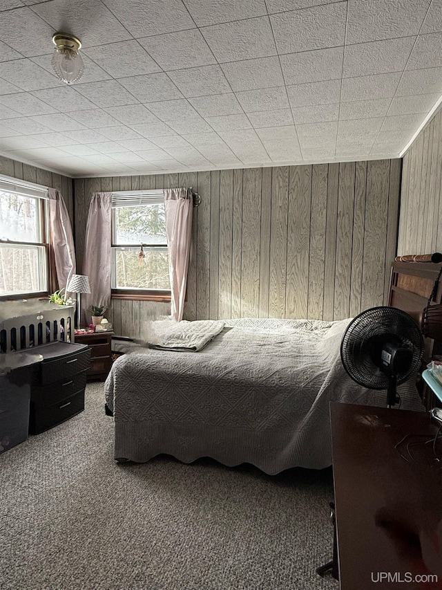 bedroom featuring wooden walls and carpet