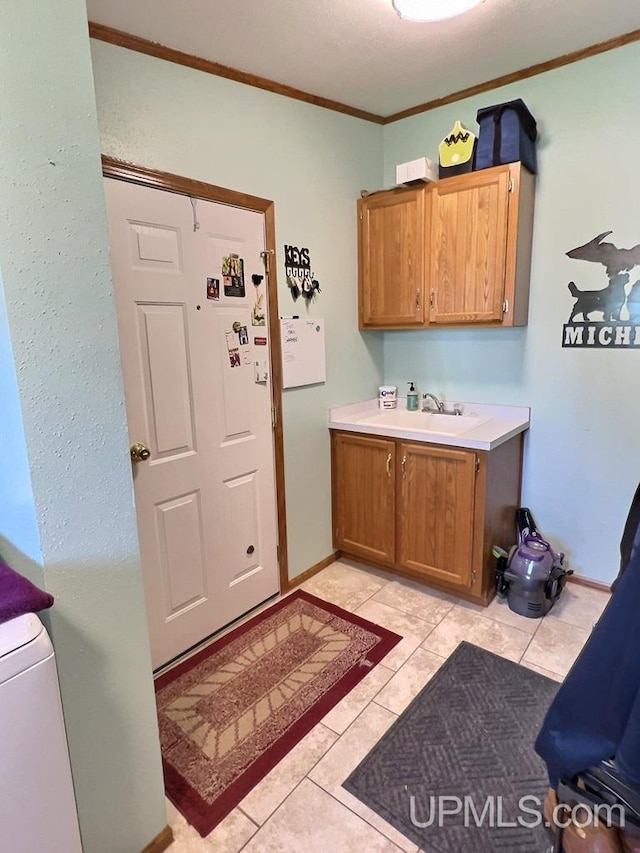 washroom with sink, light tile patterned floors, ornamental molding, and cabinets