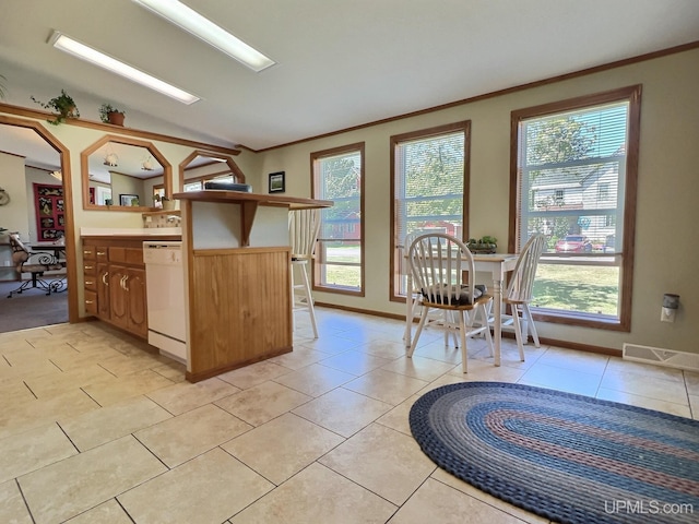 kitchen featuring white dishwasher, light tile patterned floors, crown molding, and kitchen peninsula