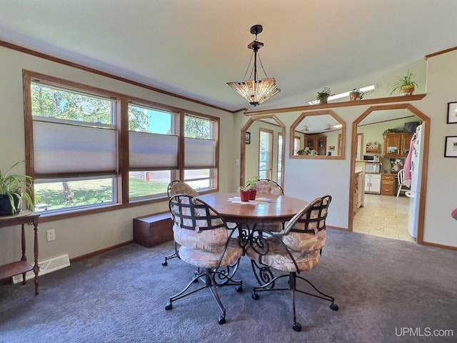 carpeted dining room with crown molding