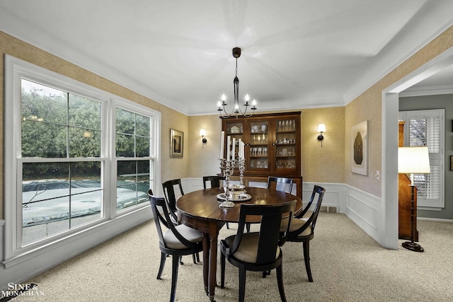 carpeted dining room featuring crown molding and an inviting chandelier