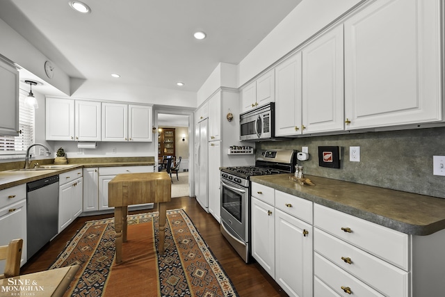 kitchen with sink, stainless steel appliances, tasteful backsplash, white cabinets, and dark hardwood / wood-style flooring