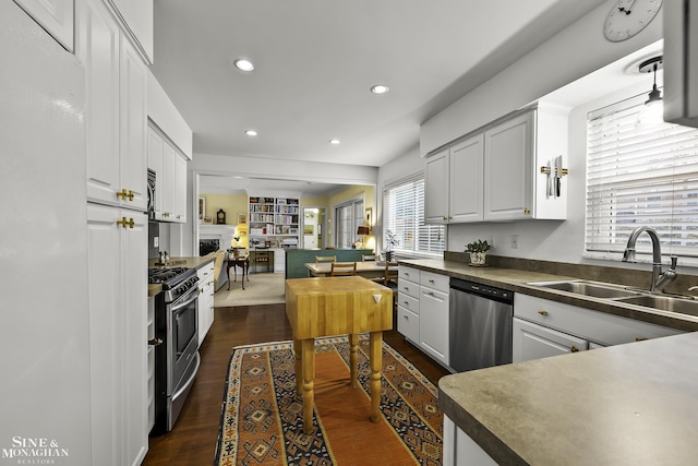 kitchen featuring appliances with stainless steel finishes, sink, dark wood-type flooring, and white cabinets