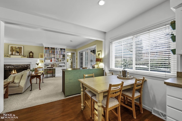 dining area with crown molding, a premium fireplace, and dark wood-type flooring