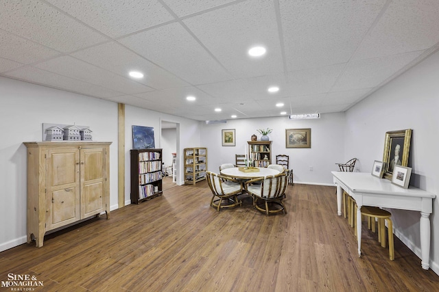 dining area featuring a drop ceiling and dark hardwood / wood-style flooring