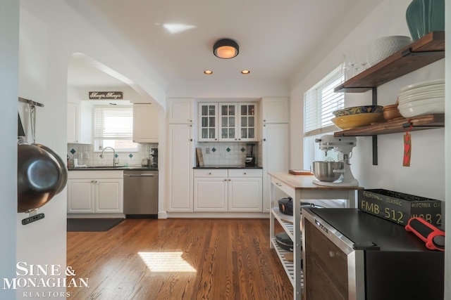 kitchen with stainless steel dishwasher, dark hardwood / wood-style floors, decorative backsplash, and white cabinets