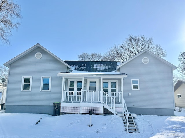 snow covered back of property with a porch