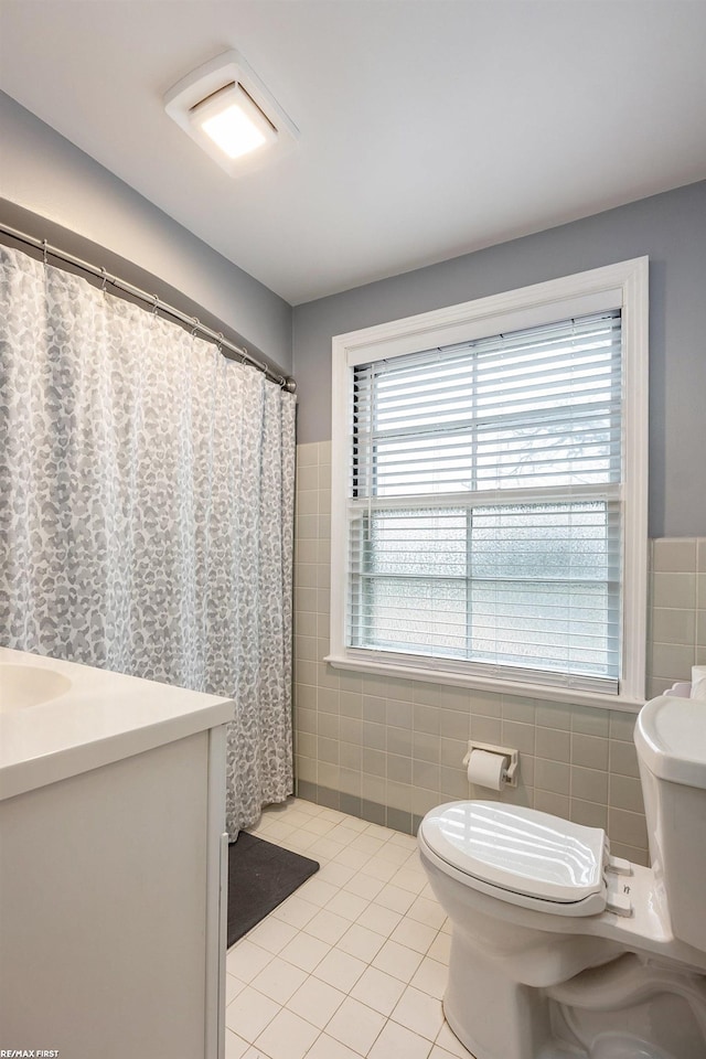 bathroom featuring tile patterned floors, toilet, a shower with curtain, tile walls, and vanity