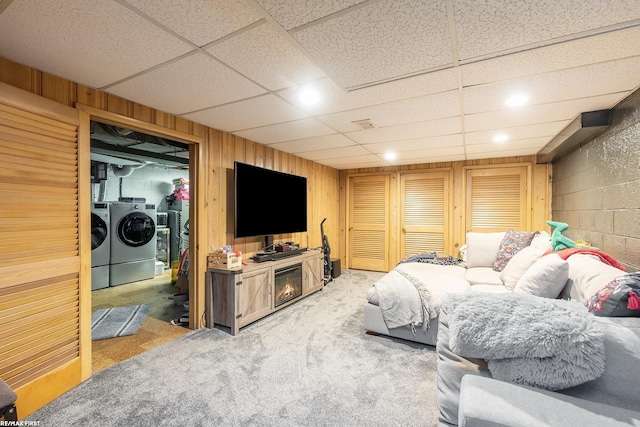 living room featuring carpet floors, washing machine and dryer, and wood walls