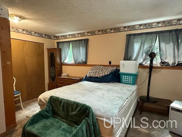 carpeted bedroom featuring a textured ceiling and a closet