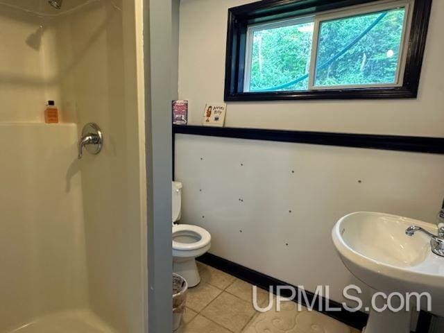 bathroom featuring toilet, sink, tile patterned floors, and walk in shower