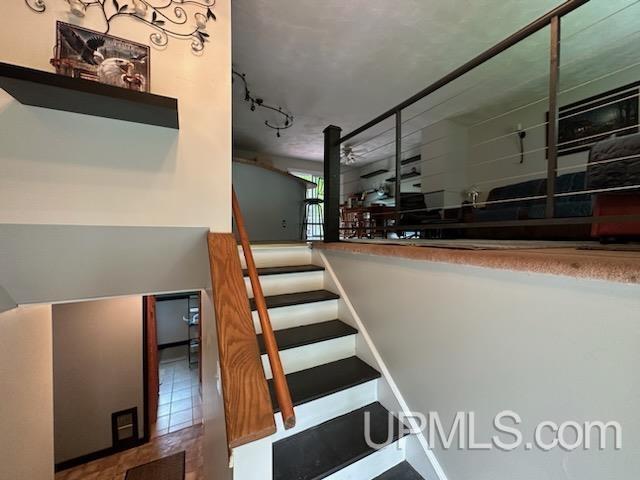 stairway with tile patterned floors and rail lighting