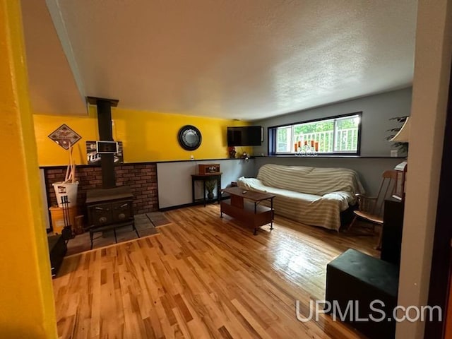 bedroom featuring wood-type flooring, a wood stove, and a textured ceiling