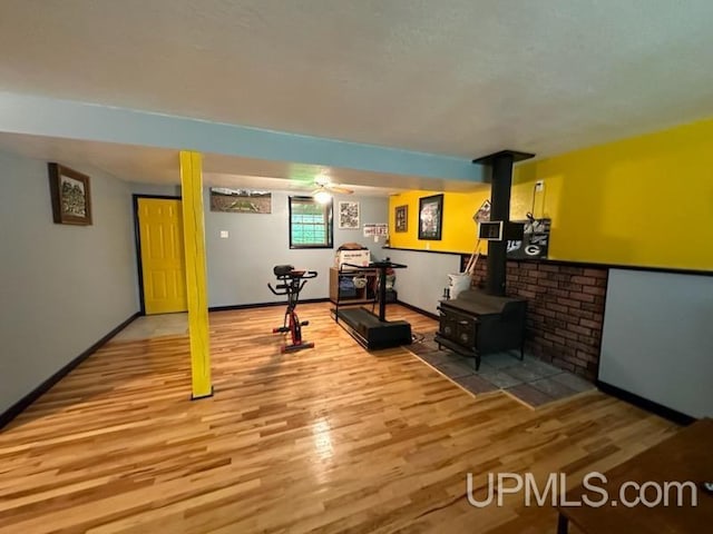 exercise room with light hardwood / wood-style floors and a wood stove