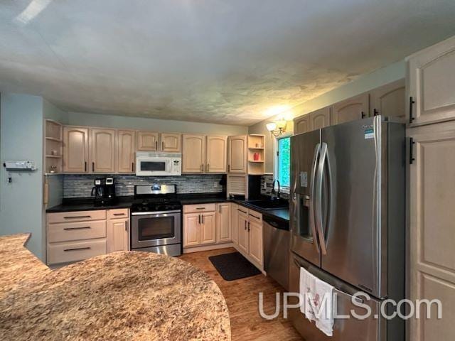 kitchen with sink, a chandelier, appliances with stainless steel finishes, dark hardwood / wood-style flooring, and decorative backsplash