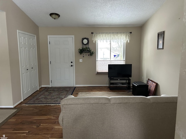 living area with dark wood-style floors, baseboards, and a textured ceiling