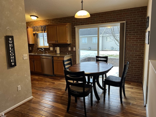 dining area with a textured wall, dark wood-type flooring, a textured ceiling, brick wall, and baseboards