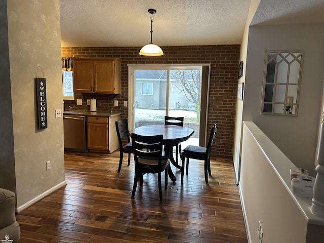 dining area with dark wood-style floors, brick wall, baseboards, and a textured ceiling