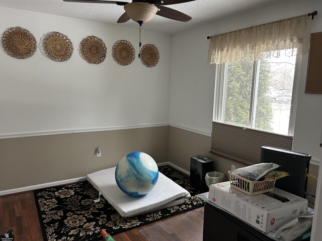 interior space featuring a textured ceiling, ceiling fan, wood finished floors, and baseboards