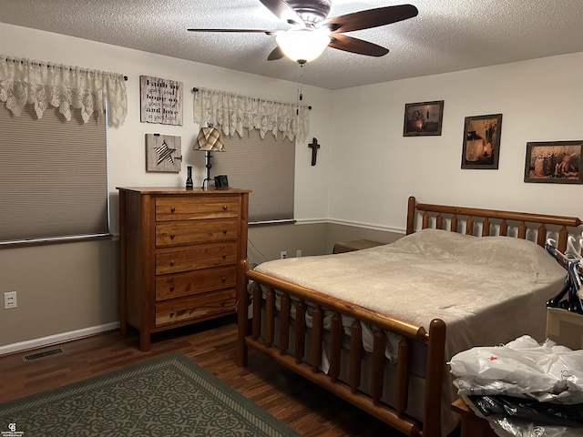 bedroom with a textured ceiling, dark wood-style flooring, a ceiling fan, visible vents, and baseboards