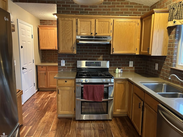 kitchen with appliances with stainless steel finishes, light countertops, a sink, and under cabinet range hood