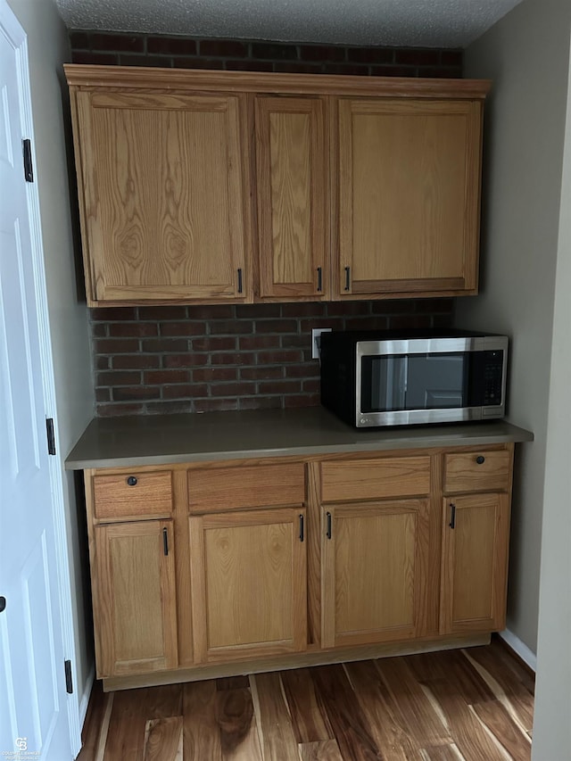 kitchen featuring tasteful backsplash, stainless steel microwave, wood finished floors, and baseboards