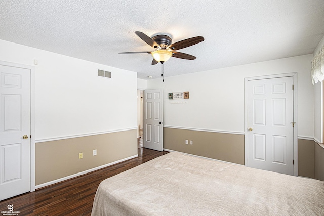 bedroom featuring dark wood-style floors, visible vents, and a textured ceiling