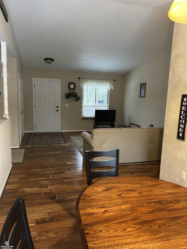 entrance foyer featuring a textured ceiling, baseboards, vaulted ceiling, and dark wood finished floors