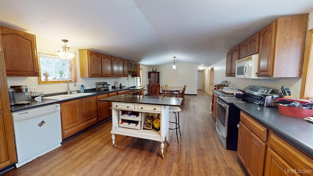 kitchen featuring vaulted ceiling, sink, hanging light fixtures, hardwood / wood-style flooring, and white appliances