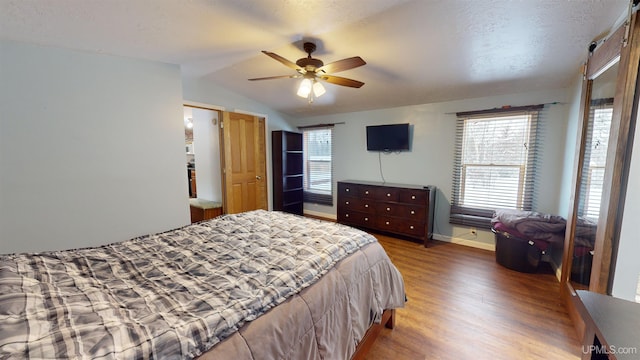 bedroom with ceiling fan, wood-type flooring, vaulted ceiling, and a textured ceiling