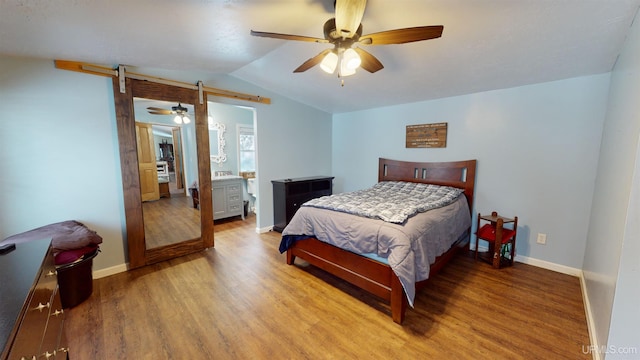 bedroom with hardwood / wood-style flooring, ceiling fan, a barn door, and vaulted ceiling