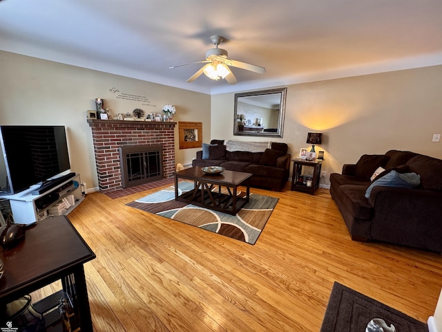 living room with ceiling fan, a brick fireplace, and light wood-type flooring