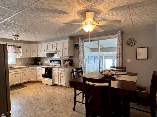 kitchen with light stone countertops, range with electric cooktop, stainless steel refrigerator, and white cabinets