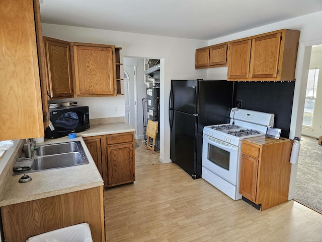 kitchen with sink, light hardwood / wood-style flooring, and black appliances