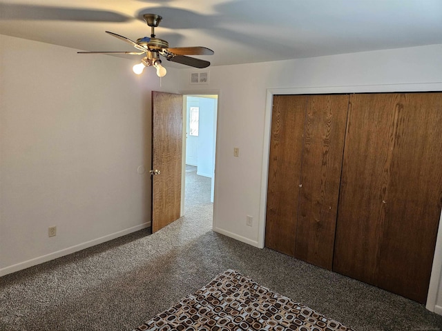 unfurnished bedroom with ceiling fan, dark carpet, and a closet