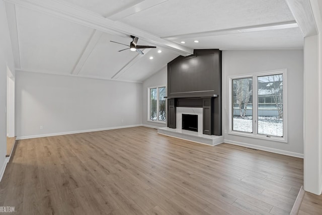 unfurnished living room featuring lofted ceiling with beams, ceiling fan, light wood-type flooring, and a high end fireplace