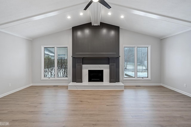 unfurnished living room featuring lofted ceiling with beams, a premium fireplace, ceiling fan, and light hardwood / wood-style flooring