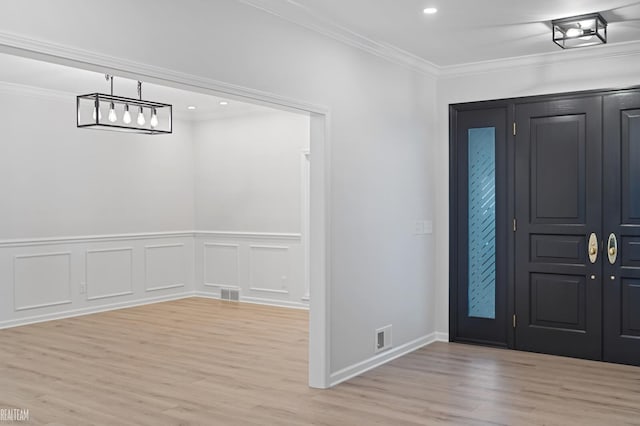 foyer featuring ornamental molding and light hardwood / wood-style flooring