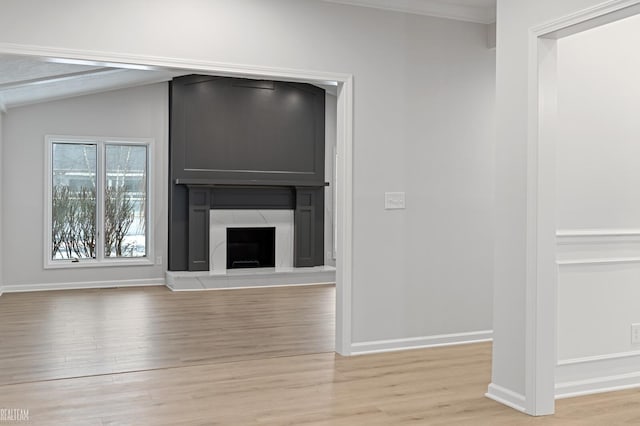 unfurnished living room with lofted ceiling, a fireplace, and light wood-type flooring