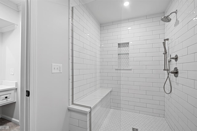 bathroom featuring ornamental molding, tiled shower, and vanity