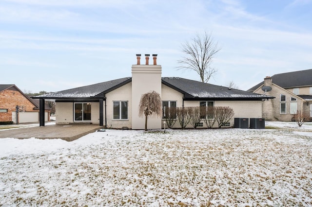 snow covered property featuring central AC unit and a patio