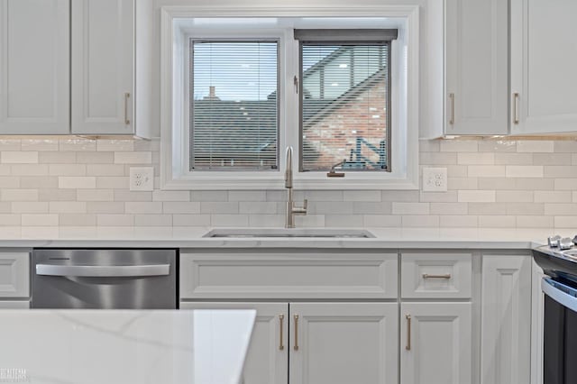 kitchen featuring tasteful backsplash, white cabinetry, sink, and stainless steel dishwasher