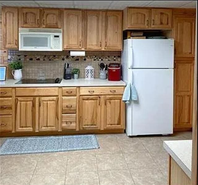 kitchen featuring backsplash, white appliances, a paneled ceiling, and light tile patterned floors