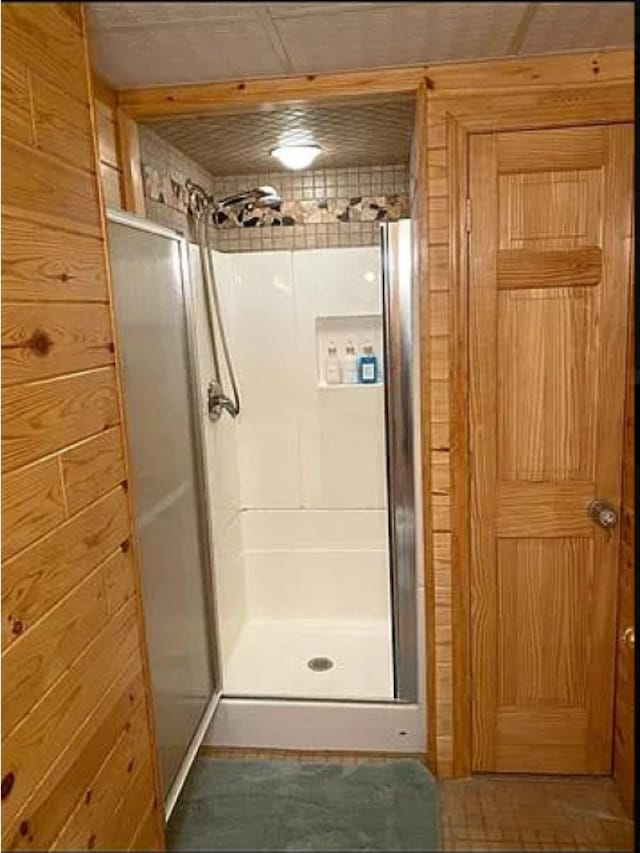 bathroom with an enclosed shower and wooden walls