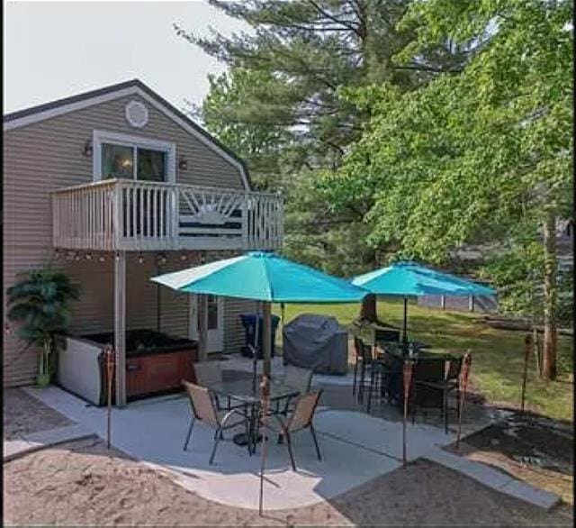 rear view of house with a hot tub, a patio, and a balcony