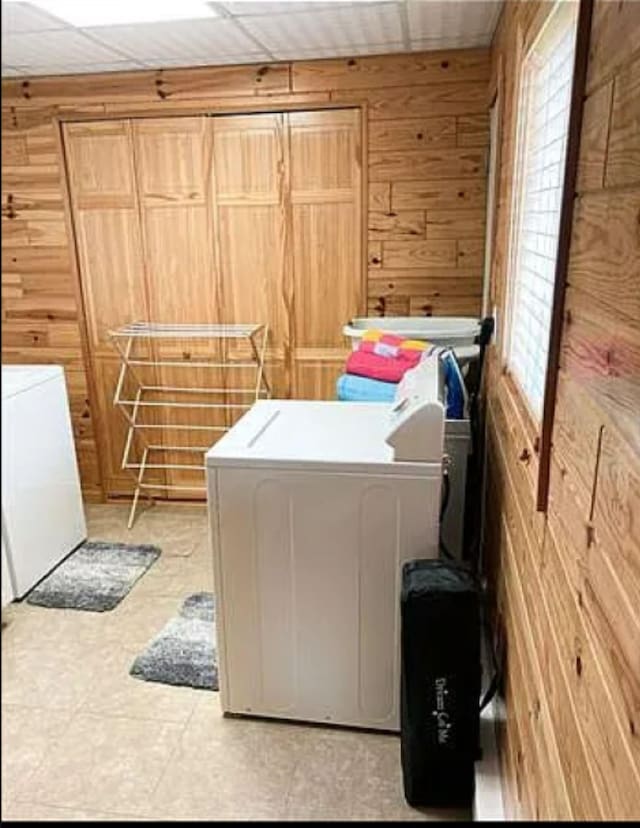 clothes washing area featuring washing machine and clothes dryer and wood walls